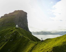 Persona in piedi su un pendio verde in un paesaggio montano