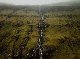 Alta cascata che scende lungo un versante erboso