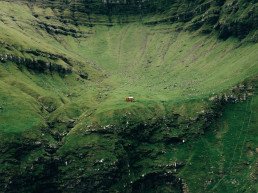 Auto rossa su una strada tra montagne verdi