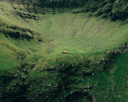 Auto rossa su una strada tra montagne verdi